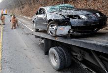 A Pontiac gets loaded onto a rollback as firefighters from Shickshinny clean debris from the roadway on Route 11 in Union Township just north of Shickshinny Wednesday afternoon. The car rolled onto its roof in a one-vehicle crash, sending two people to the hospital with minor injuries.