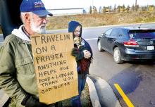 Bill Buckley holds a cardboard sign while Pam Rider holds their dog as they ask for help while standing outside the Walmart parking lot at Buckhorn on Tuesday. They said they are traveling from Maine to New Mexico and spent the little money they had to repair their old motor home. 