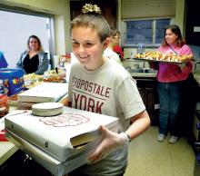 Berwick YMCA Teen Leaders member Justin Filbert, 14, carries pizza out to a buffet table during the Christmas Eve luncheon party at the Berwick Salvation Army on Tuesday. Folks who would otherwise be alone were invited to the gathering. 