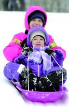 Sisters Leah, 2, front, and Lillian Rubendall, 6, Bloomsburg, sled down a hill by the Bloomsburg Town Park pool Sunday morning in Bloomsburg. The several inches of snow drew families out for sledding.