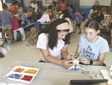 Alexa Diodata, 11, at left in photo at right, and Ivy Faleski, 12, add the final details to a robot they built. The YMCA hosted the Amazon Think Big STEM Event, in which 100 students got to build projects throughout the day