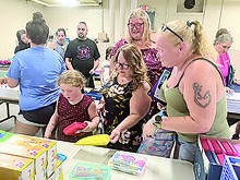 Valkyrie Hons, 5, of Bloomsburg, at left above, picks out a pencil box at the Bloomsburg Salvation Army Service Center's back-to-school supply giveaway Monday evening. She's helped by Salvation Army social worker Alicia Lindenmuth, while volunteer Brittanny Britton, second from right, and mom Elizabeth Hons look on. 