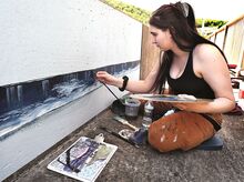 Artist Naomi O'Connell, Essex, Maryland, begins a mural along the pedestrian walkway on the Mocanaqua side of the Shickshinny-Mocanaqua bridge on Saturday. She is working from a photograph by the late Edward Steber.
