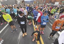 Lisa Steffes of Hazleton ties her laces amid nearly 1,300 runners on Market Street in Berwick for Thursday’s start of the 116th Run for the Diamonds.