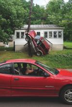 A passing driver tries to take a picture of an SUV that came to rest leaning on a broken utility pole in front of 526 Main St. in Orangeville on Monday afternoon. Police say its driver, Evan Llanso, 19, nodded off and launched the SUV into the pole. 