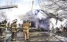 Firefighters from Bloomsburg, Buckhorn, Catawissa and Mahoning Township, above, pour water on the burning garage and upstairs apartment at 86 Harp Lane in Montour Township on Friday afternoon.