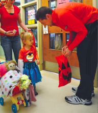Two-year-old Kaylyn Spotts, Lock Haven, gets a sticker from Bucknell University assistant basketball coach Dane Fischer during a trick-or-treat for children patients at the Janet Weis Children's Hospital at Geisinger Medical Center. 