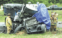 Firefighters examine the roll-off truck that slammed into the back of a tractor-trailer just west of the Lightstreet interchange Monday afternoon, killing the driver. The crash closed the westbound lanes of I-80 for more than eight hours. The highway reopened after 9:30 p.m.