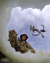 Mike Kimsey, of Stroudsburg, Pa., lowers his lure into a hole in the ice while fishing with some friends at Tobyahnna State Park on Sunday.