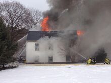 Firefighters battle a house fire along Martzville Road Monday afternoon.