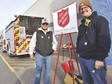 Bloomsburg firefighter Chris McGeehan, left, and Fire Captain Mike Haggerty man the Salvation Army kettle outside Walmart in Buckhorn on Monday. Bloomsburg and Berwick fire departments have agreed to a friendly competition to see which can raise the most money for the Salvation Army.