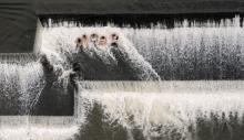 Five swimmers sit on the first level of the Benton Dam in Benton, Pa., Monday afternoon, Sept. 2, 2013, as the water flows down around them. 