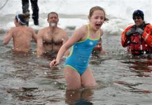 Maggie Burke, 10, of Westfield N.J., gets into the cold water up to her knees as her sister Sally, 14, and her father Patrick, left, go in further in during the third annual Paupack Plunge held at the Lighthouse Harbor Marina in Greentown Pa., Saturday, Feb. 15, 2014.