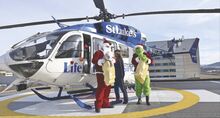 Flight nurse Tyffanny Cavanaugh helps Santa Claus and the Grinch climb out of Life Flight atop Geisinger Medical Center on Monday morning. The Christmas icons dropped off toy donations at the Janet Weis Children’s Hospital.