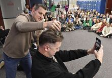 Central Columbia teacher Ryan Novak runs a trimmer through Jonathan Joseph’s hair in front of sixth grade students Monday. The haircut represented the prize for the grade that gathered the most in money and canned goods for Bloomsburg and Orangeville's Food Cupboards.