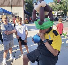 Balloon artist Lanny Lee blows up a balloon, above, as a balloon ape sits on his head at a recent Third Thursday event in Danville.