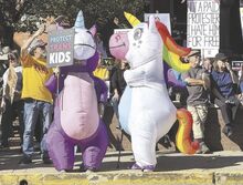 Two people wearing inflatable unicorn costumes, in photo at left above, stand in front of the Columbia County Courthouse during a No Kings rally on Saturday.