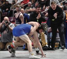 Bloomsburg's Anthony Barra, top, takes control of Conwell-Egan’s Colin Walther to win a 127-pound match by sudden victory as his assistant coach, Ryan Longenberger, background left, and coach Derek Caldwell react Thursday at the Giant Center in Hershey. See more wrestling tournament coverage starting on page 11.