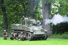 World War II reenactors portraying American troops charge the field alongside a Stuart M5 tank during a mock battle at World War II Weekend. The event continues today at Test Track Park in Berwick.
