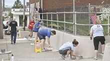 Community Giving Foundation staffers paint a wall along West Third Street at the Berwick YMCA on Friday’s Day of Caring.